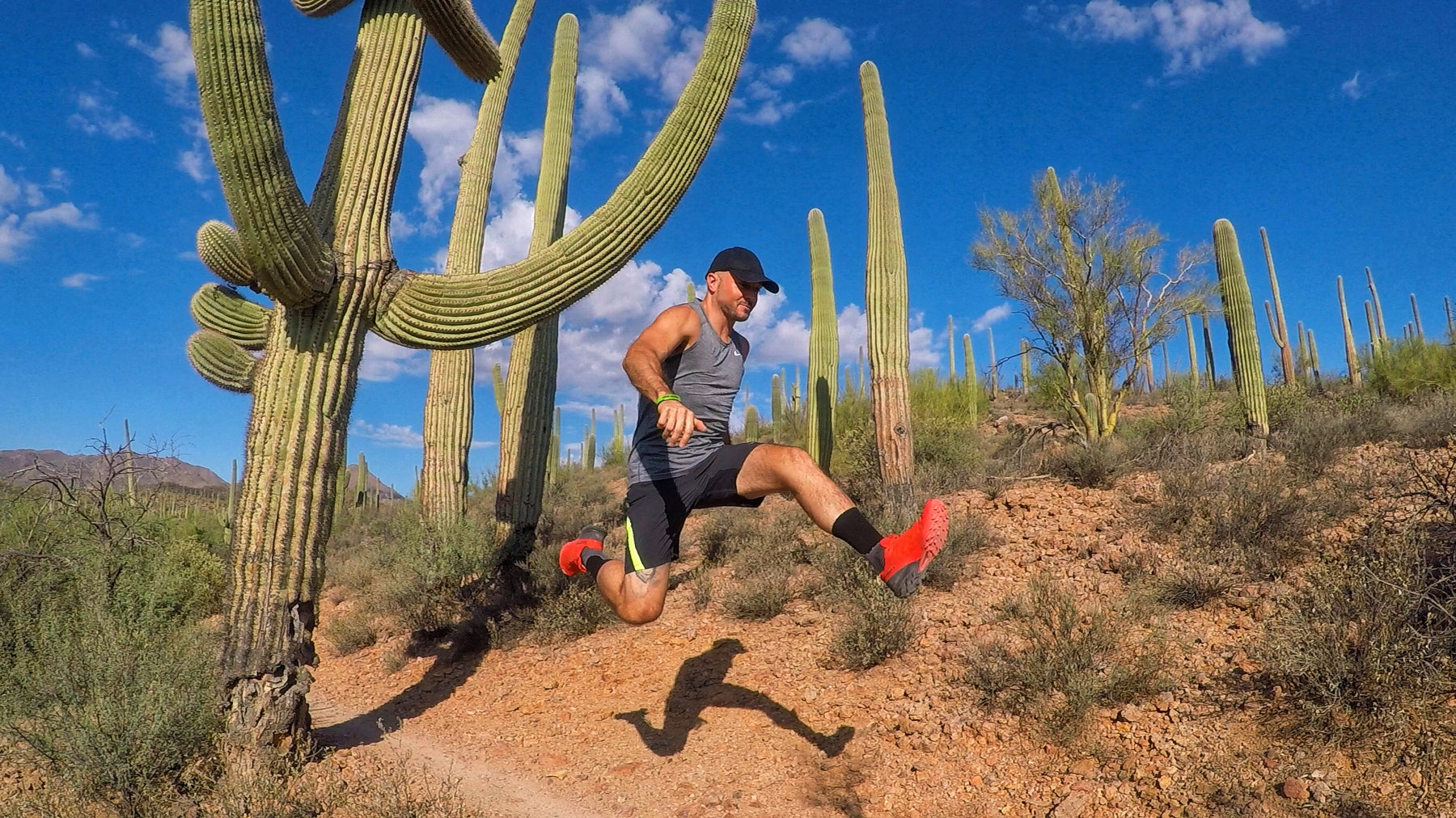 Man jumping by cactus in an Arizona ultramarathon.