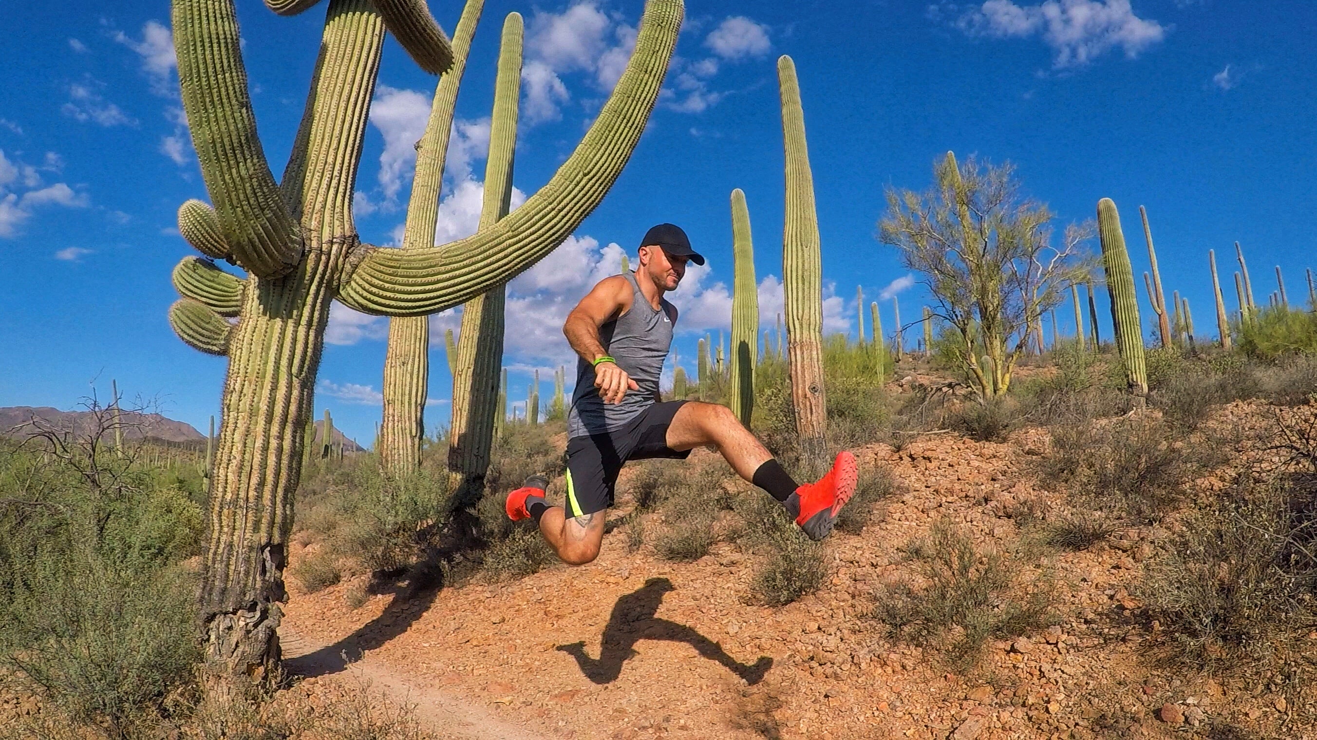 Man jumping by cactus in an Arizona ultramarathon. 