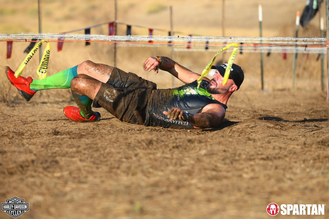 Man running under tape wearing green compression socks for running.