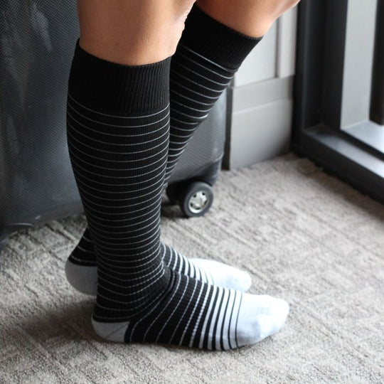 Athlete relaxing in their Sox Solution over the calf socks in black and white stripes